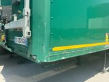 a green truck with a yellow stripe parked in a lot