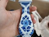 a person holding a blue and white vase in their hand