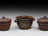 trois casseroles marron avec leurs couvercles, posées les unes à côté des autres sur une surface blanche
