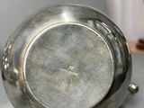 a silver bowl sitting on a table next to a vase