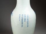 a white vase with blue writing on it sitting on a table
