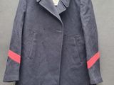 Le manteau est suspendu à un cintre accroché au mur.