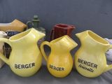 three yellow jugs are lined up on a table with other items