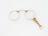 pair of gold plated eyeglasses with a chain on a white background