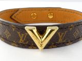 a close up of a brown leather bracelet with a gold v on it