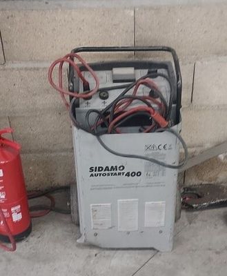 un extincteur rouge à côté d'une pile de matériel électrique