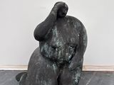 une statue représentant un homme assis sur un plancher en bois