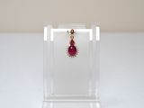 earrings in a clear display case with a red bead hanging from it