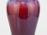 un vase violet posé sur une surface blanche