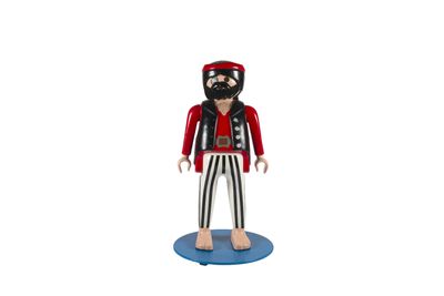 La figurine représentant un homme barbu vêtu d'une veste rouge est posée sur un socle bleu.