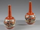 une paire de vases orange ornés de motifs floraux sur fond gris