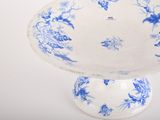 a blue and white bowl on a pedestal on a table