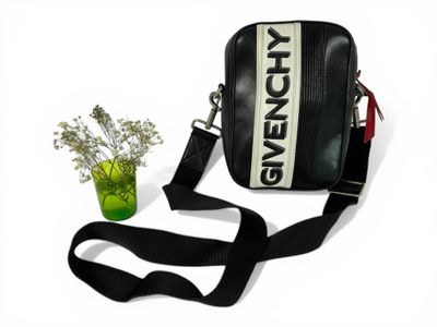 sac à bandoulière noir et blanc, avec une bandoulière noire et une fleur dans un vase vert