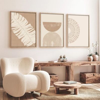 un salon avec un fauteuil, une table et deux tableaux accrochés au mur