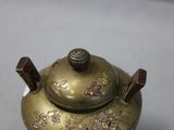 a small brass teapot with a lid on a table