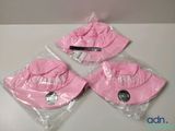 trois chapeaux roses sont emballés dans des sacs en plastique sur une table