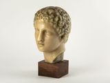 marble bust of a young man with curly hair on a wooden base