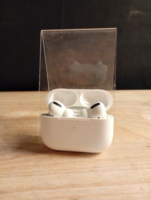 une paire d'AirPods posée dans une boîte transparente sur une table