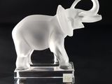 un éléphant en verre posé sur un socle transparent