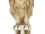 une petite chouette perchée au sommet d'un socle blanc