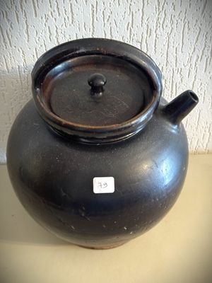 un pot noir posé sur une table, avec une étiquette dessus