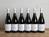 six bouteilles de vin rouge alignées sur une table en bois