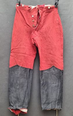 un vieux pantalon rouge accroché à un porte-vêtements