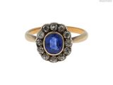 gros plan d'une bague avec une pierre bleue entourée de diamants blancs