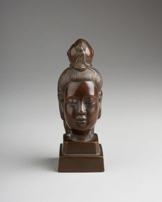 a bronze statue of a woman with a bird on her head