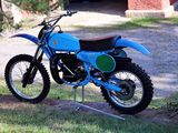 a blue dirt bike that is parked in the grass
