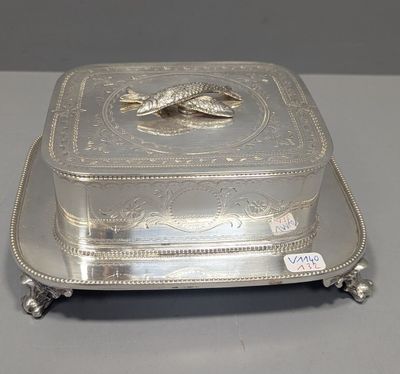 un plat ancien en argent orné d'un poisson, posé sur un socle