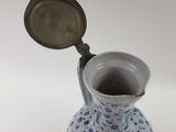 a small blue and white vase with a silver lid