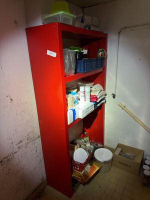 une armoire rouge dans un coin d'une pièce, sur laquelle sont posés de nombreux objets