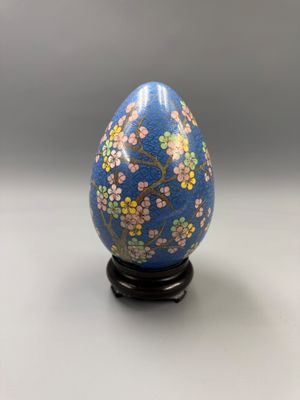 un gros plan d'un œuf bleu sur lequel sont peintes des fleurs