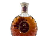 une photo d'une bouteille de brandy posée sur une surface blanche