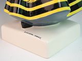 a black and yellow fish statue on a white base