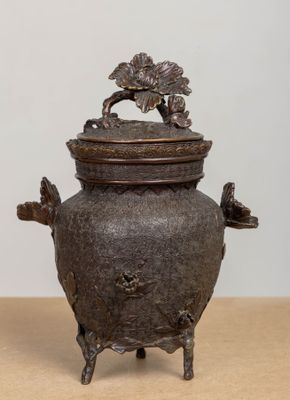 un petit pot en métal surmonté d'un oiseau