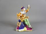 une figurine représentant un homme assis sur une chaise, tenant un oiseau dans la main