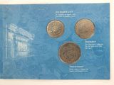 three coins on a blue book with a picture of a building in the background