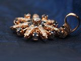 an image of a close up of a gold broochle on a blue cloth
