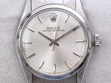 une photo d'une montre Rolex argentée posée sur une surface blanche