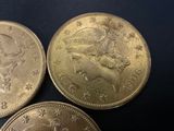 three gold coins sitting on top of each other on a black surface