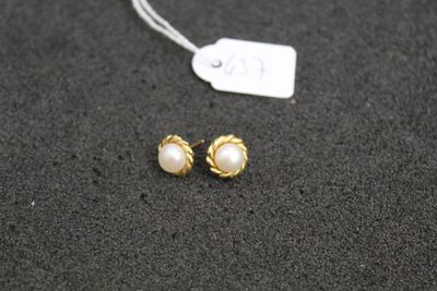 a pair of gold and pearl earrings on a black surface