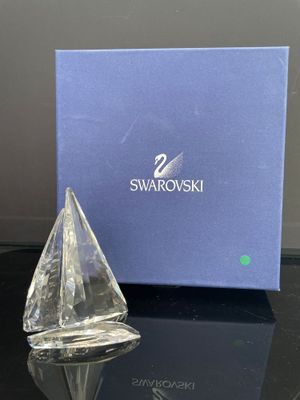 le petit voilier en cristal est posé sur une table, à côté d'une boîte bleue