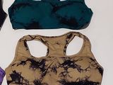 three women ' s sports bra tops are lined up on a white surface