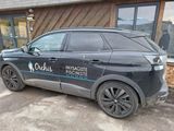 une voiture noire garée devant un immeuble sur lequel est accrochée une pancarte