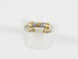 gros plan d'une bague en or et en argent sur une surface blanche