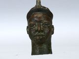 une image représentant une tête d'homme en bronze, avec un oiseau perché sur le sommet de sa tête