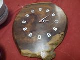 une horloge en bois posée sur une table où se trouvent des assiettes et des tasses