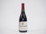 une bouteille de vin rouge posée sur une table blanche